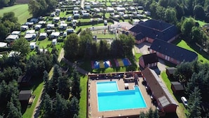 Eine Vogelperspektive eines Campingplatzes mit Wohnmobilen, einem Schwimmbad und einem großen Gebäude.