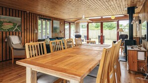 A spacious wooden dining area with a long table and multiple chairs, large windows, and a view of the outdoors. - 4 Star Holiday Home in Hadsund (Hadsund)
