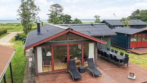 A modern house with a large deck, a glass-enclosed room, and a view of the sea. - 4 Star Holiday Home in Hadsund (Hadsund)