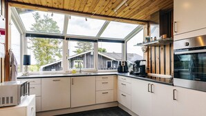 A modern kitchen with a large window, built-in appliances, and a dark tiled floor. - 4 Star Holiday Home in Hadsund (Hadsund)