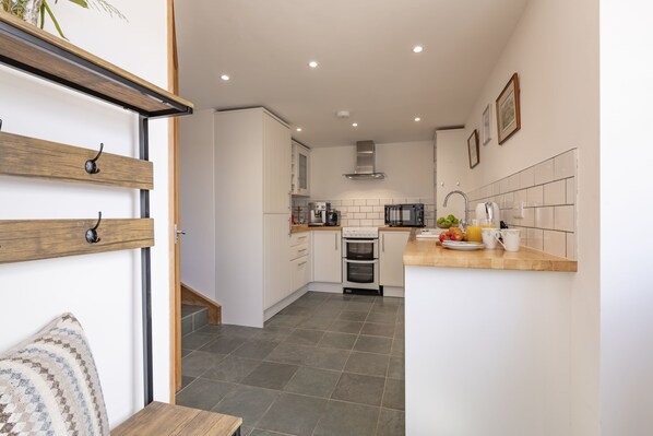 A modern kitchen with white cabinets, a built-in oven, and a wooden countertop.