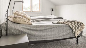 A bedroom with a bed, a bedside table, a lamp, and a window. - 2 Person Holiday Park Home in Bastad (Bastad)