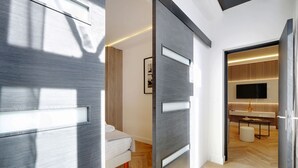 A modern hotel room with a large bed, a TV, and a seating area with a table and ottoman. - The Upper Marais Superb Apartment for 6 People (Paris)
