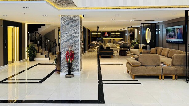 A modern lobby with a marble column, sofas, a TV, and a staircase. - KARACA HOTEL VAN (Van)