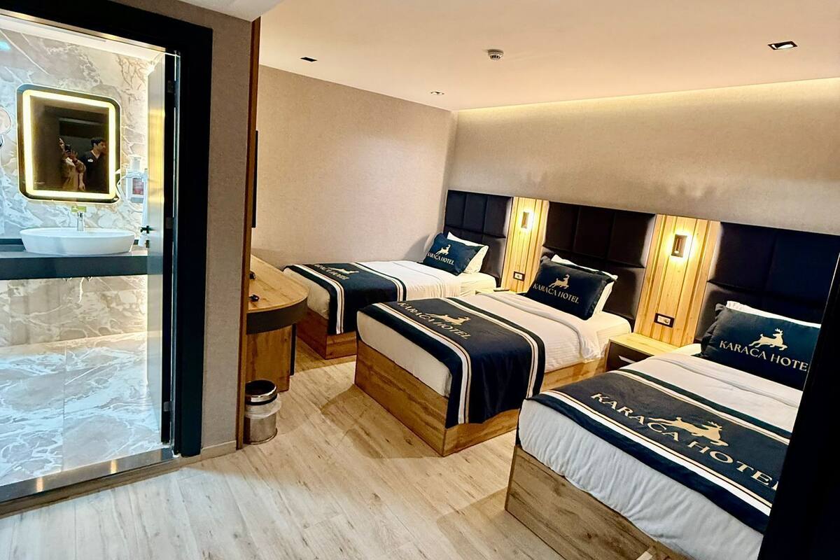 Una habitación de hotel moderna con dos camas, un baño y un ventanal grande.