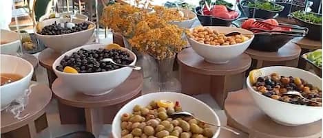 Un buffet con diversi cibi, tra cui olive, frutta e verdura.