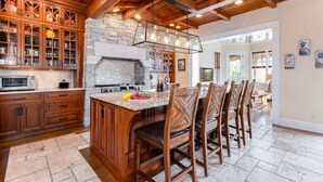 Una cocina amplia con armarios de madera, una chimenea de piedra y una isla grande con taburetes de bar.