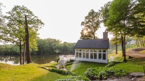Una casa con un muelle que se adentra en un lago, rodeada de exuberante vegetación y árboles.