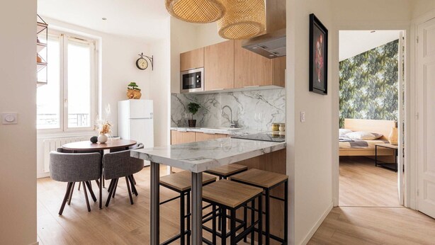 A modern kitchen with a marble countertop, wooden cabinets, and a dining area with bar stools. - DIFY Paul Bert - Part-dieu (Lyon)