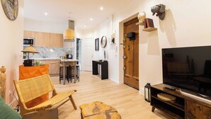 A modern living room with a TV, wooden furniture, a kitchen in the background, and a dining area. - DIFY Paul Bert - Part-dieu (Lyon)