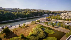A riverside view with a boat dock, a park area, and buildings along the riverbank. - DIFY Paul Bert - Part-dieu (Lyon)