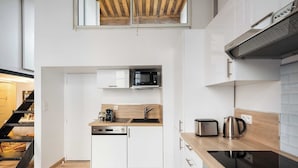 A compact kitchen with white cabinets, a microwave, a toaster, and a coffee maker.
