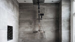 A shower area with a modern design, featuring a wall-mounted showerhead and a handheld showerhead.