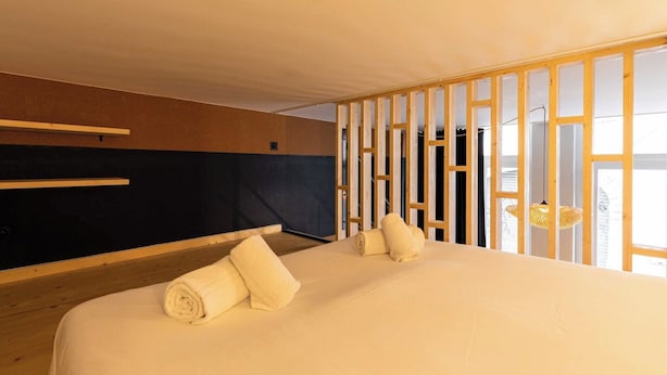 Ein Hotelzimmer mit Bett, Holz-Kopfteil, einem Fenster mit Aussicht und einer Pendelleuchte.