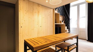 Ein Holztisch mit Bänken in einem Raum, dessen Wand ebenfalls aus Holz besteht und der eine Treppe besitzt.