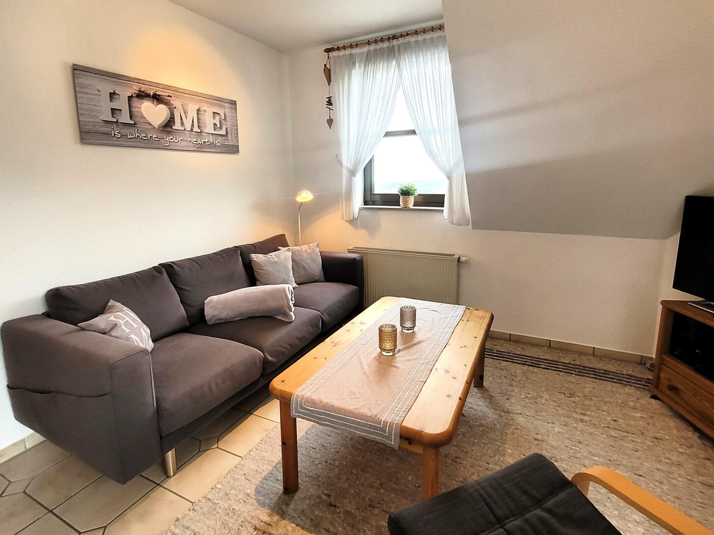 A cozy living room with a dark brown sofa, a wooden coffee table, and a television on a wooden stand.