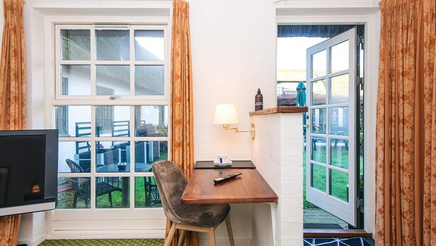 A small room with a desk, chair, and a television. There is a window with curtains, a door, and a view of the outside. - 2 Person Holiday Park Home in Fano (Fano)