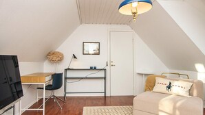 A compact room with a wooden desk, a chair, a sofa with a cushion, a patterned rug, and a ceiling light fixture. - 2 Person Holiday Park Home in Fano (Fano)