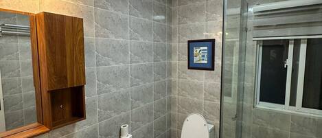 A modern bathroom with a shower, toilet, and sink.