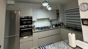 Una cocina moderna con electrodomésticos de acero inoxidable, encimera de mármol y alfombra a rayas.