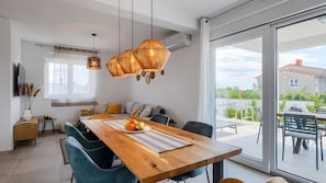 Un espace repas moderne avec une table en bois, des chaises bleues et une grande fenêtre donnant sur l’extérieur.