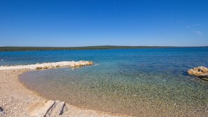 Une plage côtière aux eaux calmes et au sable clair, bordée de formations rocheuses.