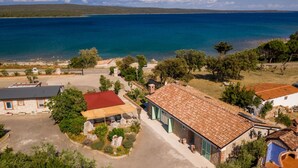 Une propriété située sur la côte, avec un bâtiment en pierre, une construction à toit rouge et une vue dégagée sur la mer.