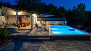 A well-lit outdoor pool area with lounge chairs, a hot tub, and a covered seating area. - Villa Klarita - Makarska by Villas Guide (Drum)