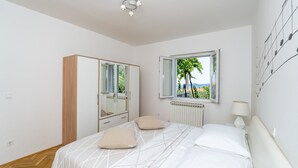 A bedroom with a bed, a wardrobe, a window with a view, and a ceiling light. - Villa None Kate by Villas Guide (Dubrovnik)