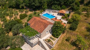An aerial view of a property with a swimming pool, a covered patio, and a stone building with a tiled roof. - Villa None Kate by Villas Guide (Dubrovnik)