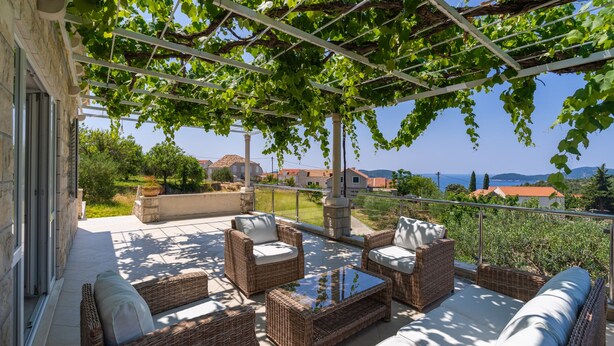 A covered outdoor seating area with wicker furniture and a view of the sea. - Villa None Kate by Villas Guide (Dubrovnik)