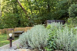 Un jardín con un farol de piedra, un banco de madera y una cerca de madera.