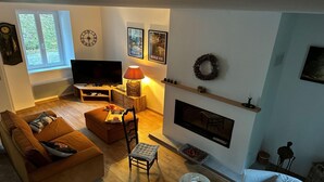 A living room with a sofa, a chair, a TV, a fireplace, and framed pictures on the wall. - Cottage by River with Spa near Carcassonne (Caudebronde)