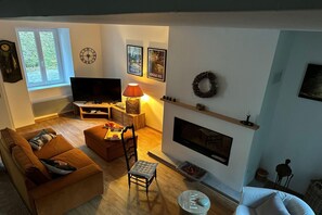 A living room with a sofa, a chair, a TV, a fireplace, and framed pictures on the wall. - Cottage by River with Spa near Carcassonne (Caudebronde)