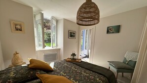 A bedroom with a bed, a chair, a hanging light fixture, and a window. - Cottage by River with Spa near Carcassonne (Caudebronde)