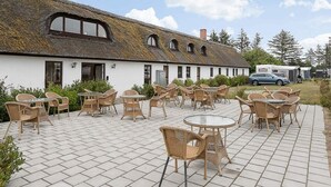 A building with a thatched roof, outdoor seating area with wicker chairs and tables, and a paved patio. - 6 Person Holiday Park Home in Fjerritslev (Fjerritslev)