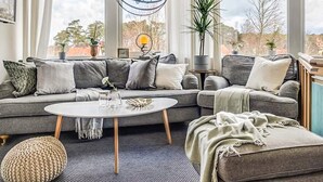 A modern living room with a grey sectional sofa, a round coffee table, and a hanging light fixture. - 2 Person Holiday Park Home in Bastad (Bastad)