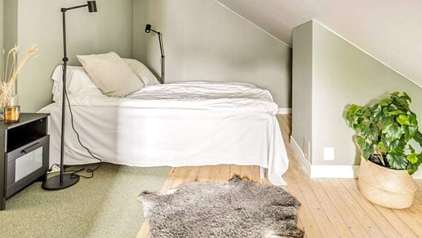 A bedroom with a bed, bedside lamps, a small table, a plant, and a rug. - 2 Person Holiday Park Home in Bastad (Bastad)