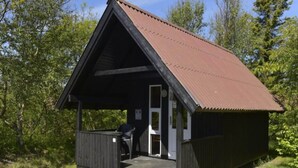 A small wooden cabin with a sloped roof and a porch. - 4 Person Holiday Park Home in Pandrup (Pandrup)