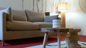 Un salon avec un canapé beige, une petite table en bois et un lampadaire.