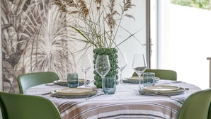A dining table set with plates, glasses, and a vase with dried plants. - Charming holiday home near Tanchet beach (Les Sables-d´Olonne)
