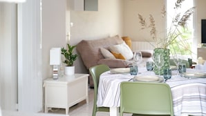 A dining area with a table set for four, a sofa in the background, and a potted plant on a side table. - Charming holiday home near Tanchet beach (Les Sables-d´Olonne)