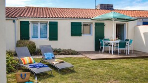 A patio with two lounge chairs, a table with chairs, and a striped umbrella. - Charming holiday home near Tanchet beach (Les Sables-d´Olonne)