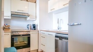 A modern kitchen with white cabinets, a stainless steel oven, a dishwasher, and a sink. - Charming apartment in the Presidents' District (Les Sables-d´Olonne)