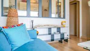 A modern living room with a blue sofa, a woven basket, and a minimalist console table. - Charming apartment in the Presidents' District (Les Sables-d´Olonne)