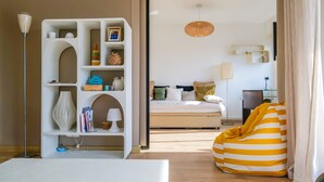A modern hotel room with a bed, a bean bag, a white shelving unit, and a hanging light fixture. - Charming apartment in the Presidents' District (Les Sables-d´Olonne)
