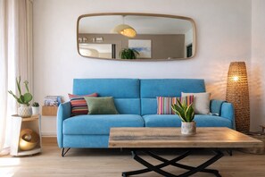 Un canapé bleu, une table basse en bois, un miroir au mur et une lampe.