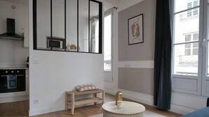 A modern living room with a sofa, a round coffee table, a small wooden bench, and a large mirror. - Apartment for 2, Ideal Location in Downtown Angers (Angers)