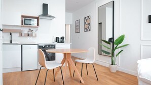 Uma cozinha moderna com armários brancos, micro-ondas, fogão e área de jantar com mesa redonda e duas cadeiras.