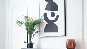 Interior moderno com lareira, um vaso de planta e uma obra de arte abstrata emoldurada na parede.